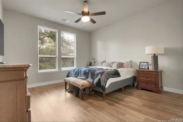 a spacious bedroom with a bed and wooden floor
