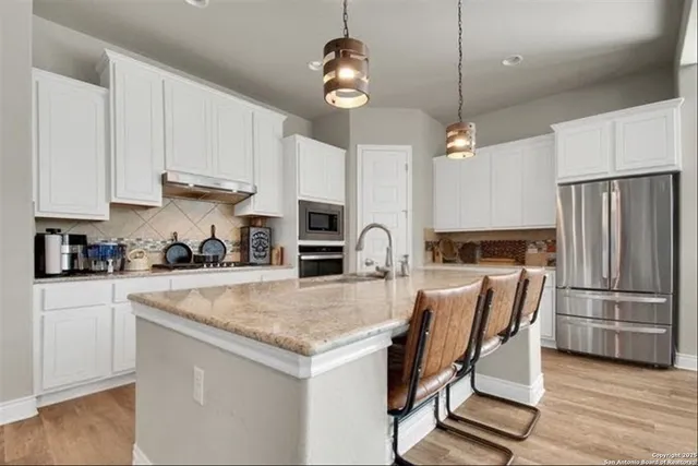 a kitchen with granite countertop a table chairs stove and refrigerator