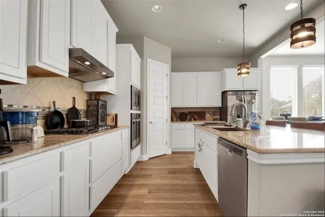 a kitchen with stainless steel appliances granite countertop a sink a stove and a refrigerator