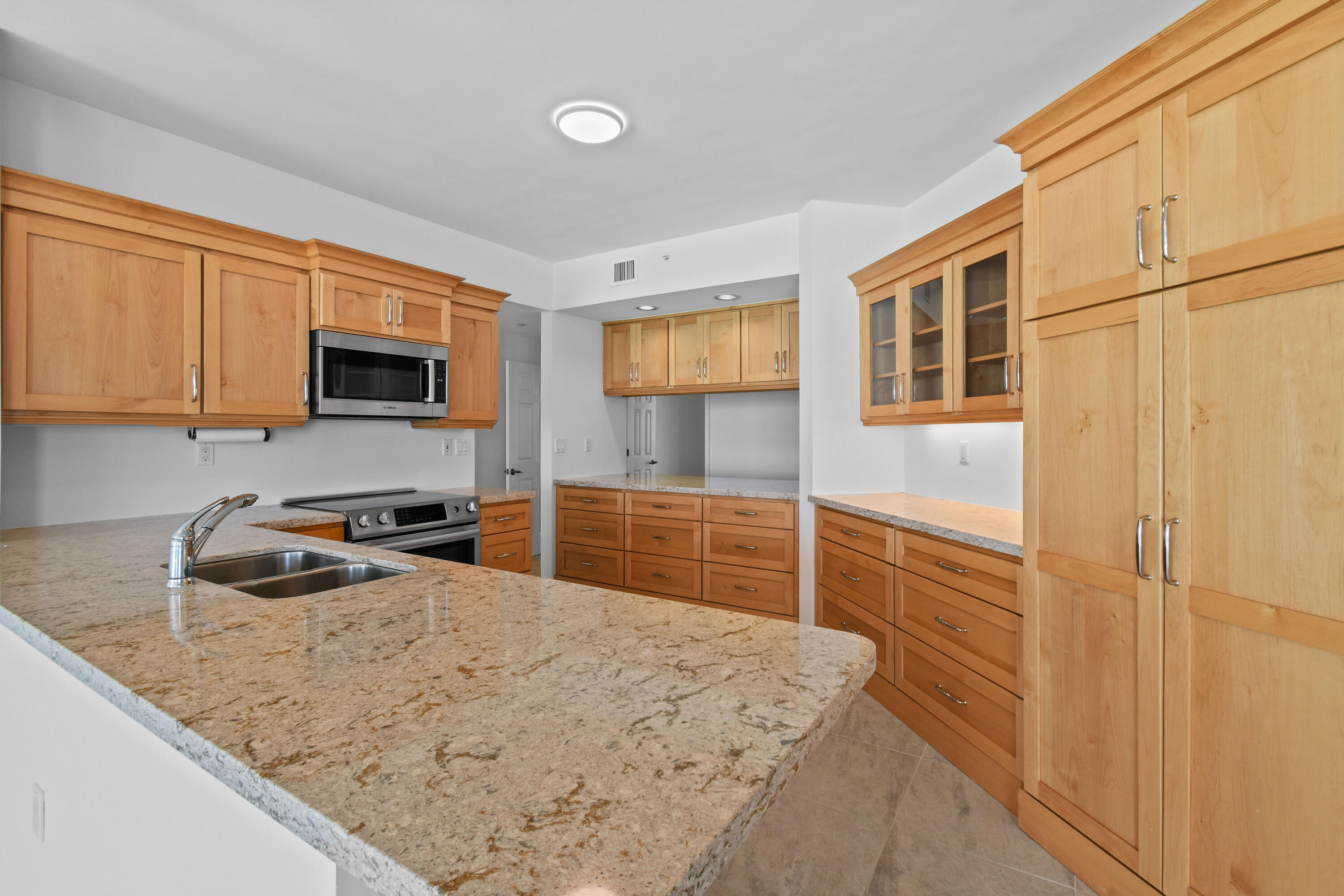 1660 Florida A1A, Unit 352 Jupiter, FL 33477 - Photo 8 of 36 a kitchen with granite countertop a sink a stove top oven a counter space and cabinets