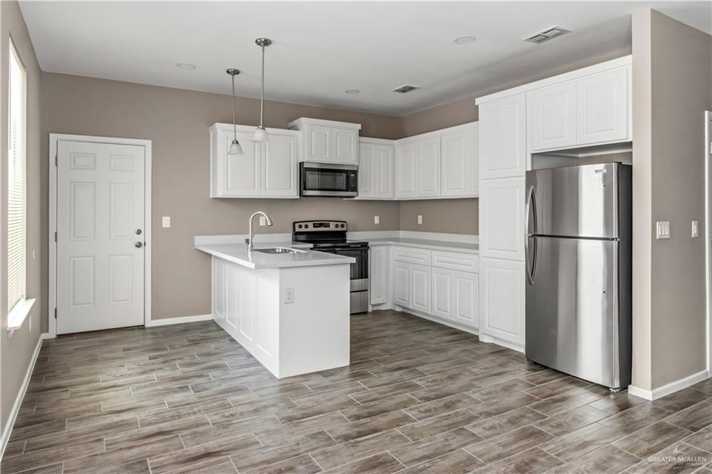 1314 Beverly Avenue, Unit 2 Weslaco, TX 78596 - Photo 7 of 11 Kitchen with white cabinetry, appliances with stainless steel finishes, kitchen peninsula, decorative light fixtures, and sink
