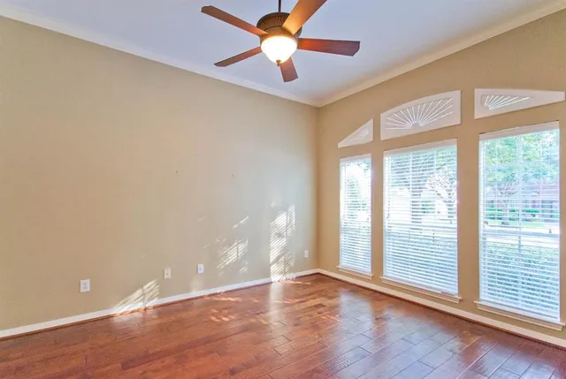 a view of an empty room with wooden floor and a window