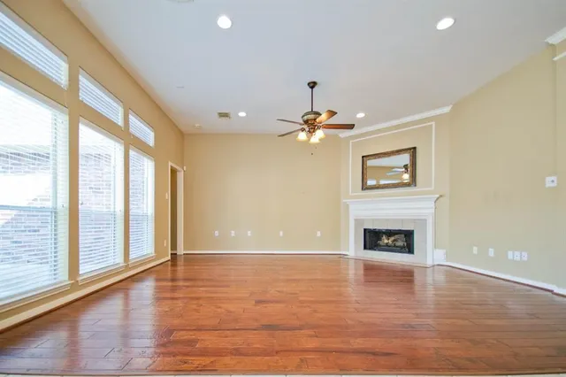 a view of an empty room with window and wooden floor
