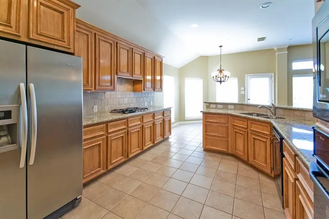a large kitchen with stainless steel appliances granite countertop a sink and cabinets