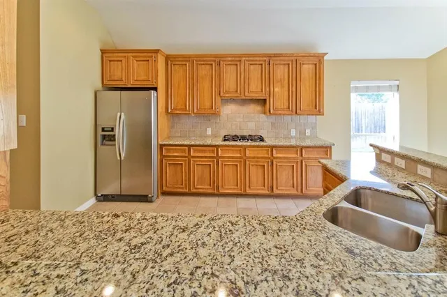 a kitchen with stainless steel appliances granite countertop a refrigerator a sink and a stove
