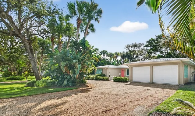 a front view of a house with a garden and trees