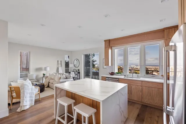 a large kitchen with a counter space a sink appliances and living room view