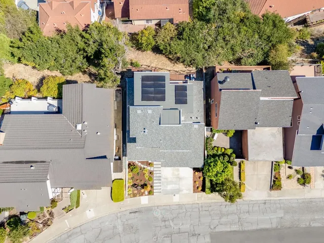 an aerial view of a house with large trees and flower plants