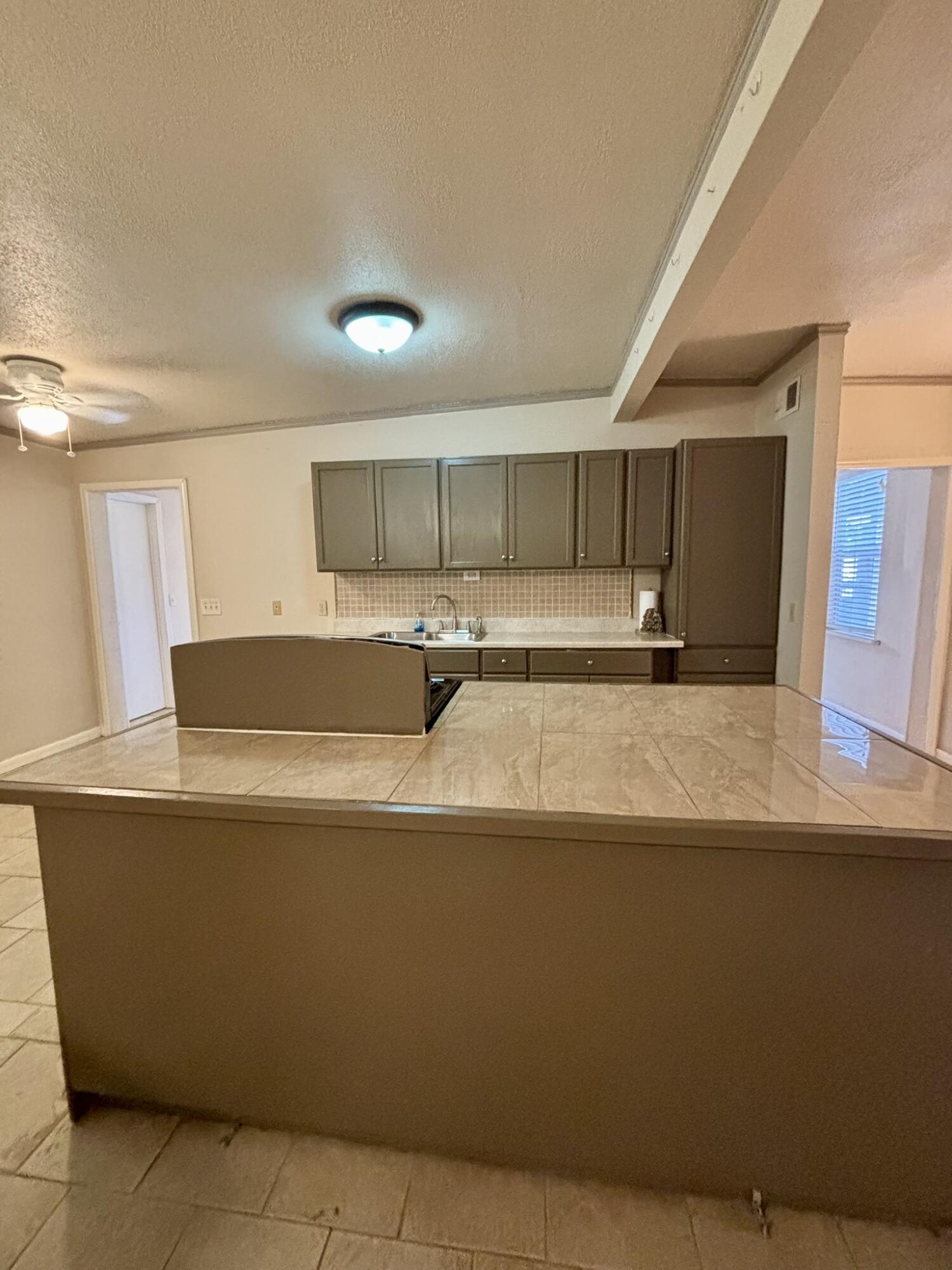 2313 47th Street Lubbock, TX 79412 - Photo 5 of 17 a view of a kitchen with kitchen island a sink wooden floor and a refrigerator