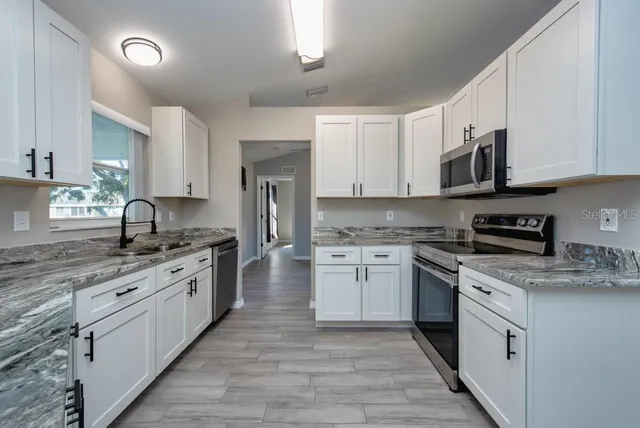 a kitchen with stainless steel appliances granite countertop a stove top oven a sink dishwasher and a refrigerator