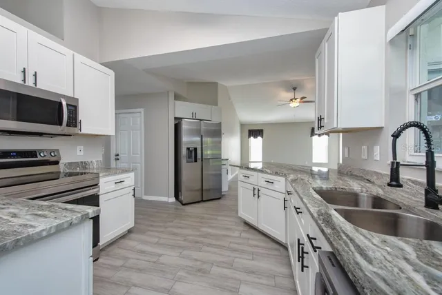 a large kitchen with granite countertop a large counter top stainless steel appliances and cabinets