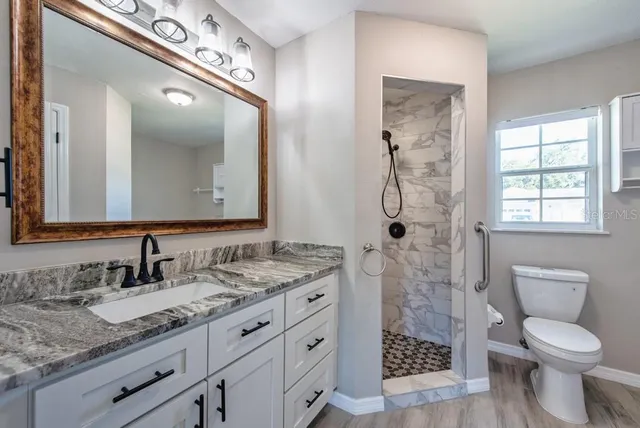 a bathroom with a granite countertop sink toilet and shower