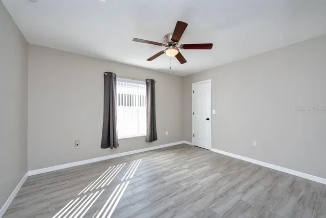 a view of an empty room with wooden floor and a window