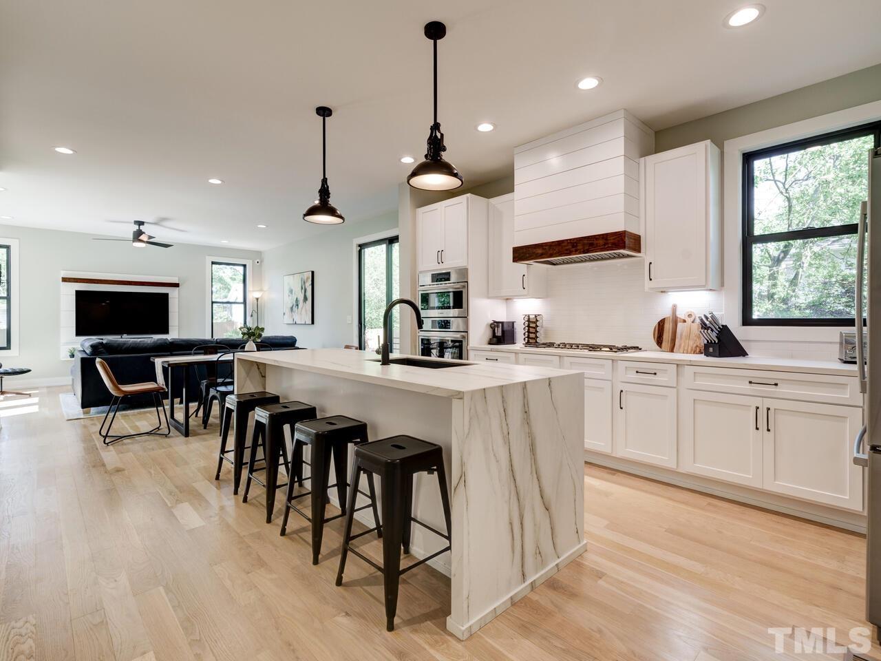220 Hargrove Street Durham, NC 27701 - Photo 12 of 76 a kitchen with stainless steel appliances kitchen island granite countertop a stove a sink a dining table and chairs with wooden floor