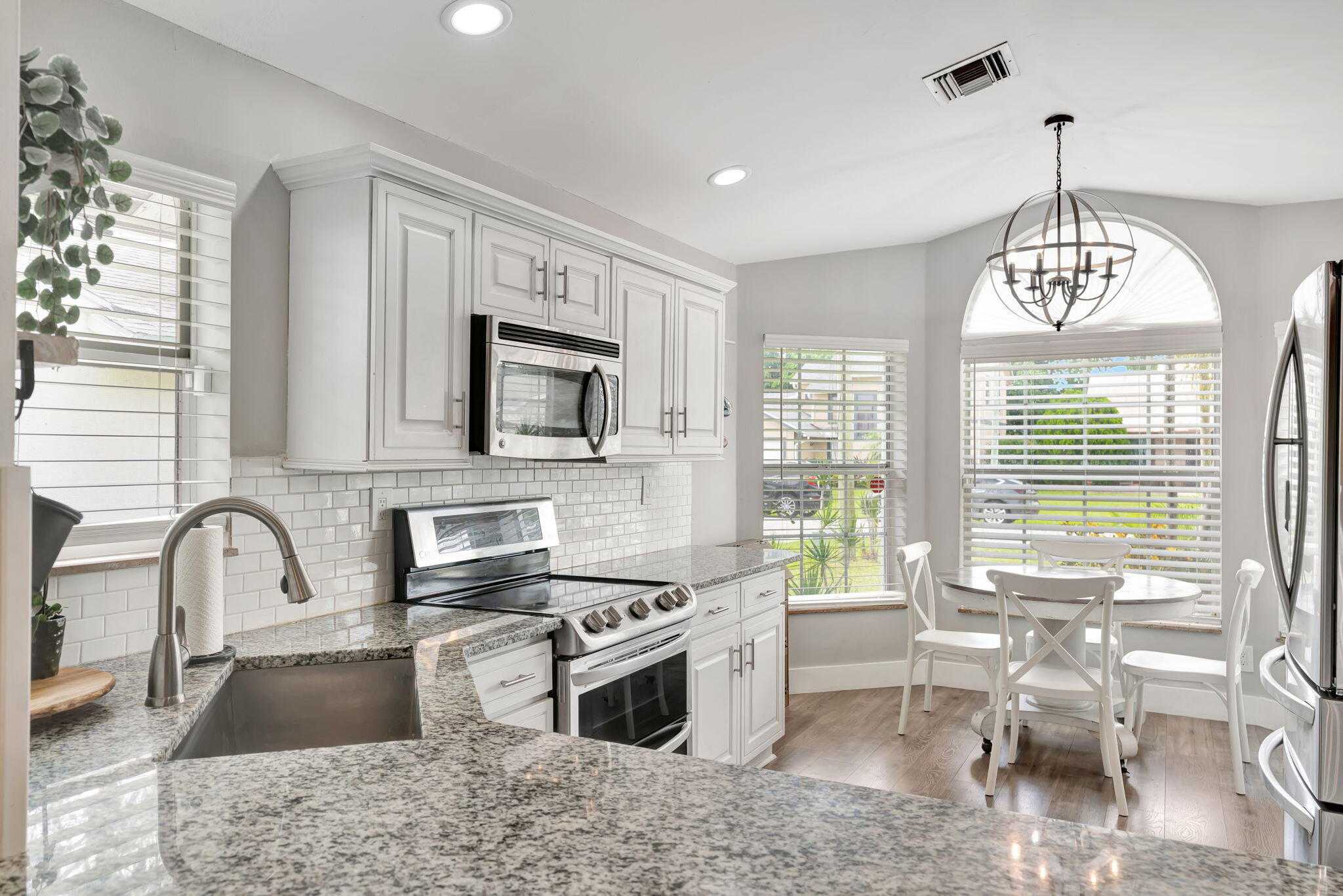 6247 Ungerer Street Jupiter, FL 33458 - Photo 15 of 36 a kitchen with stainless steel appliances granite countertop a stove top oven a sink a dining table and chairs