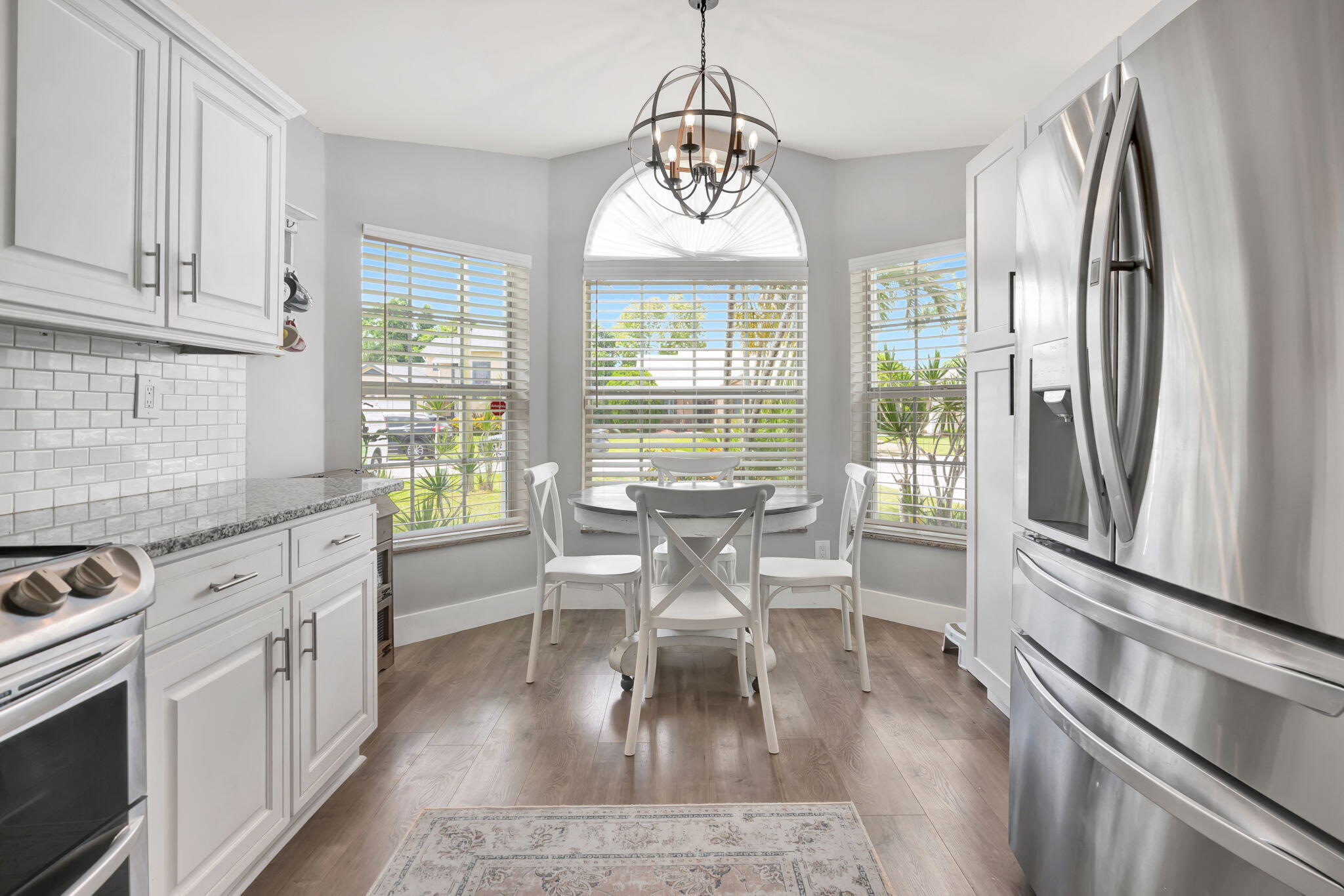 6247 Ungerer Street Jupiter, FL 33458 - Photo 16 of 36 a dining room with wooden floor a chandelier a wooden table and chairs