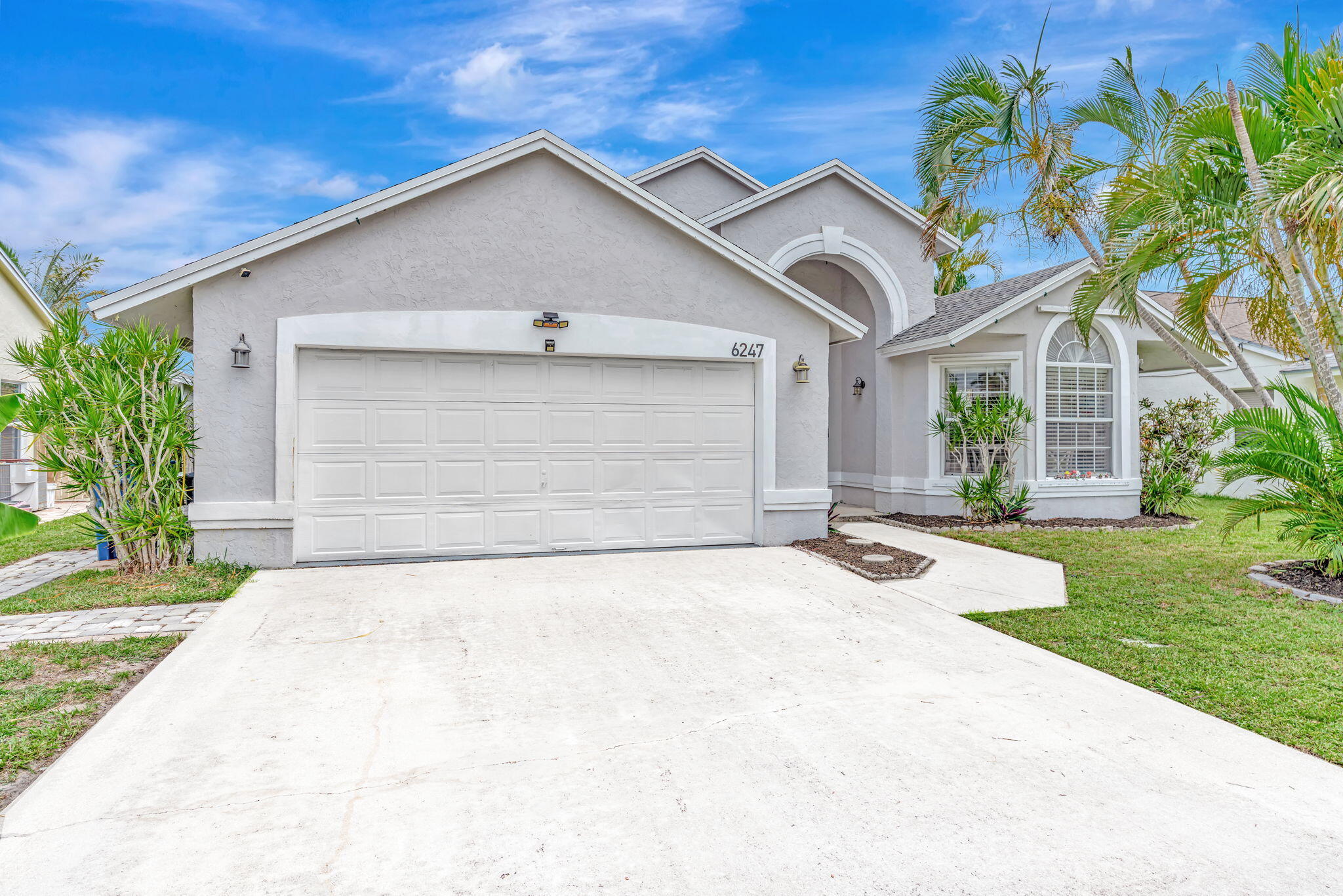 6247 Ungerer Street Jupiter, FL 33458 - Photo 2 of 36 a front view of a house with a yard and garage