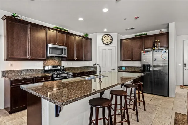 a kitchen with granite countertop a stove a sink dishwasher a dining table and chairs with wooden floor