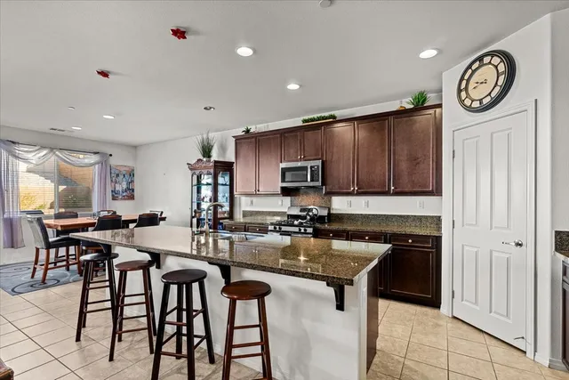 a kitchen with granite countertop a table chairs a stove a sink and a refrigerator