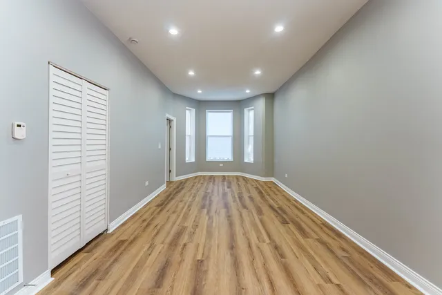 a view of empty room with wooden floor and fan