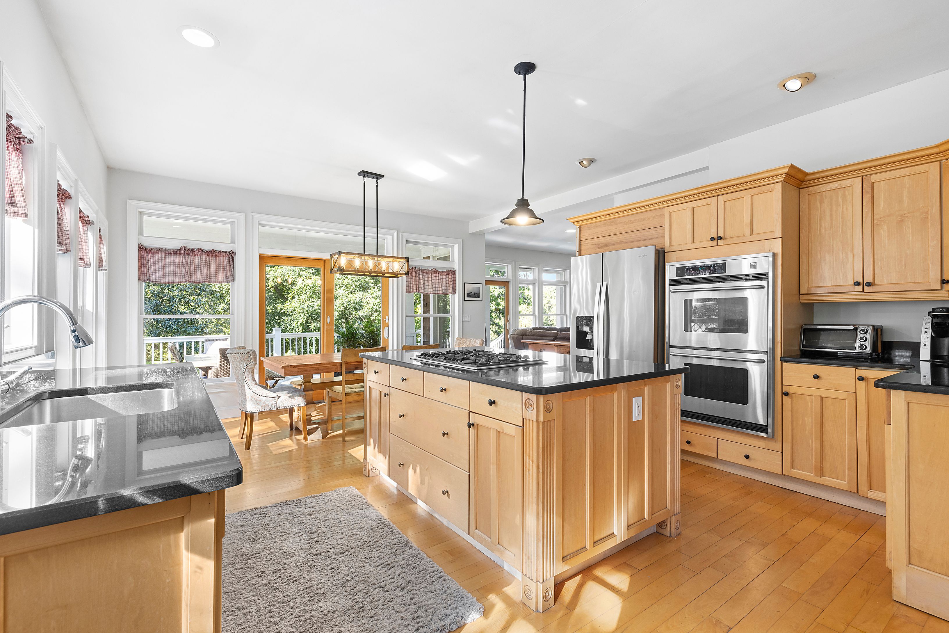 4 Bayberry Road Montauk, NY 11954 - Photo 5 of 29 a kitchen with stainless steel appliances granite countertop a stove top oven a sink dishwasher a dining table and chairs with wooden floor