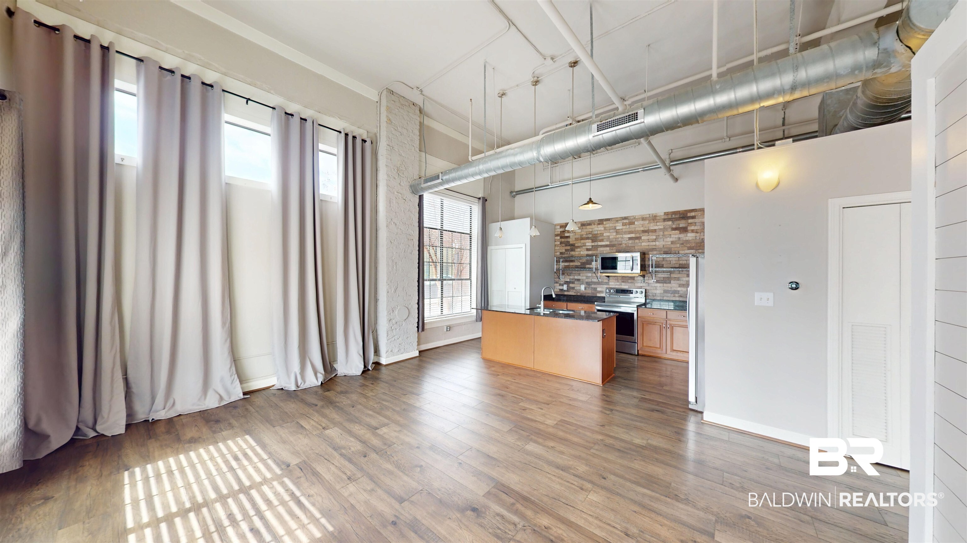 308 St Louis Street, Unit 101 Mobile, AL 36602 - Photo 22 of 30 Kitchen featuring dark countertops, a center island, appliances with stainless steel finishes, a high ceiling, and light wood-type flooring