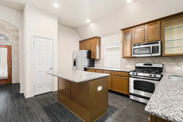 a kitchen with stainless steel appliances granite countertop a stove a sink and a microwave