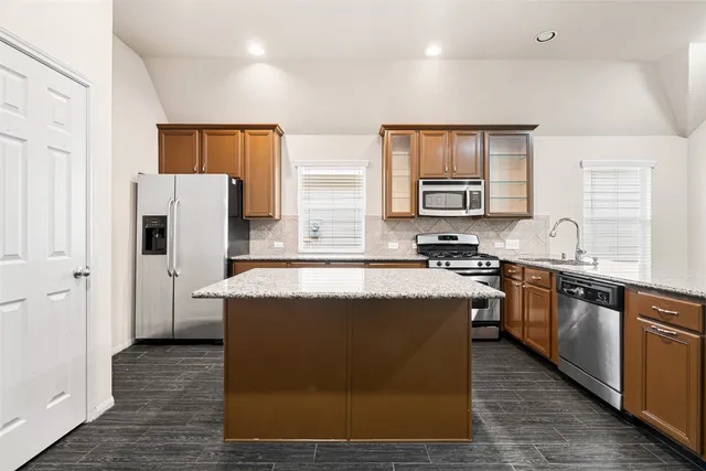 a kitchen with stainless steel appliances granite countertop a stove a sink a refrigerator and a microwave