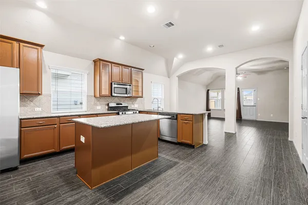 a large kitchen with stainless steel appliances granite countertop a large counter top a sink and a wooden floors