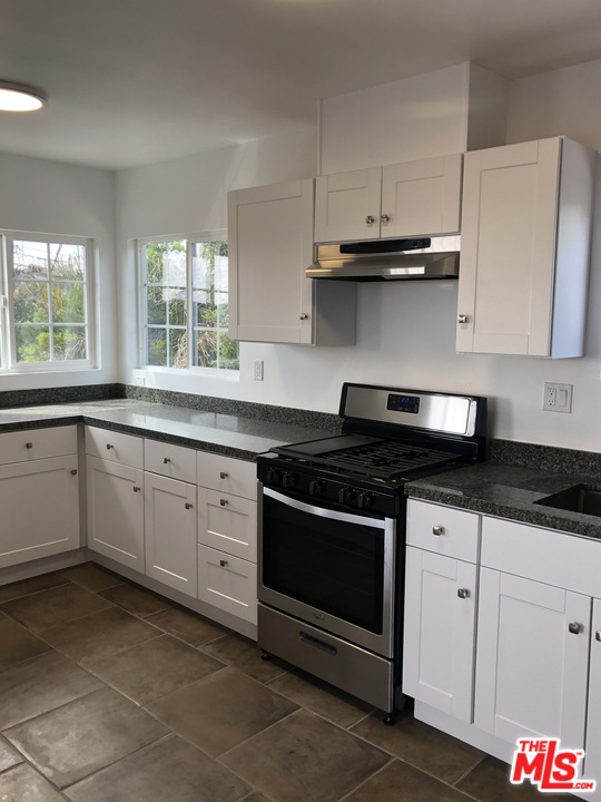 a kitchen with stainless steel appliances granite countertop white cabinets granite counter tops and a wooden floors
