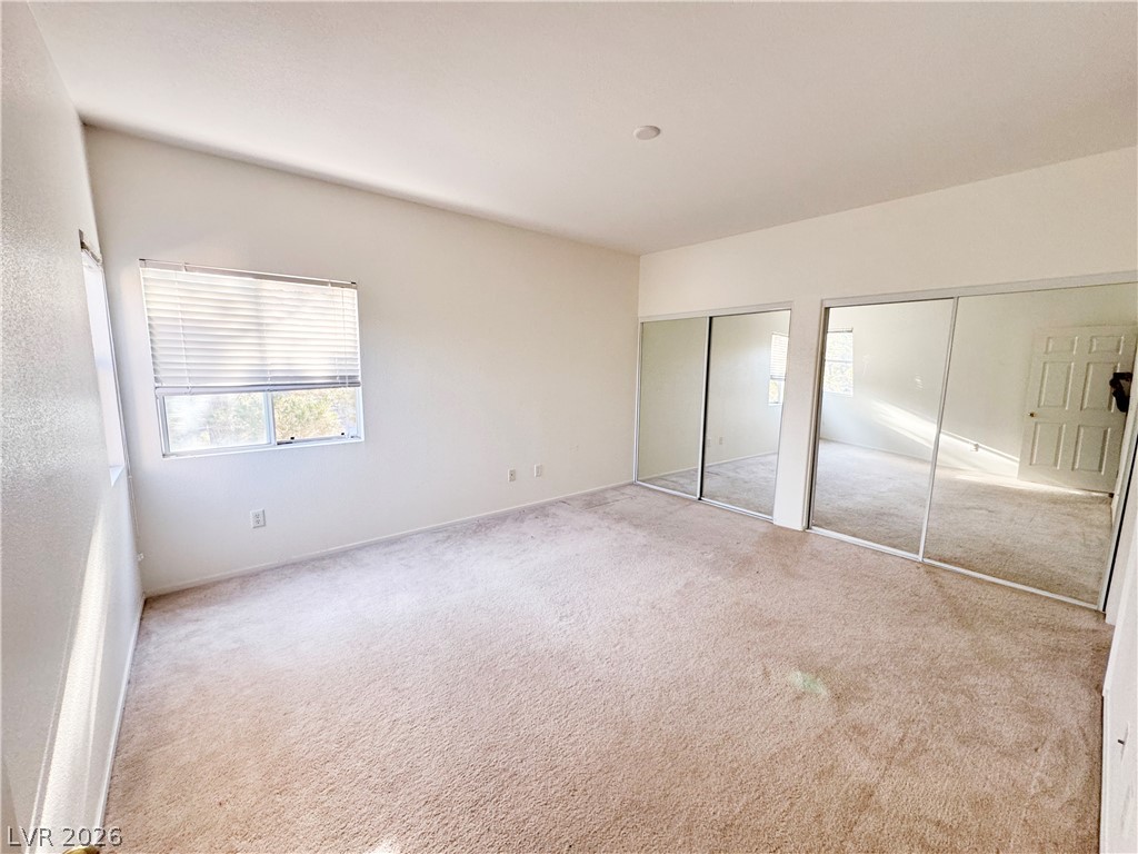 9580 West Reno Avenue, Unit 242 Las Vegas, NV 89148 - Photo 14 of 26 Bright bedroom with plush carpeting, offering mirrored closet doors and abundant natural light.