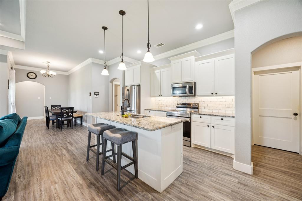 709 Coblestone Circle Mabank, TX 75147 - Photo 6 of 24 a kitchen with stainless steel appliances granite countertop wooden floors stove and white cabinets