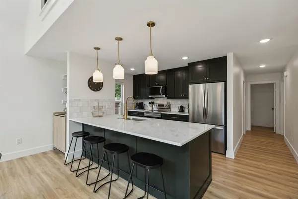 a kitchen with stainless steel appliances kitchen island granite countertop a table chairs and a refrigerator