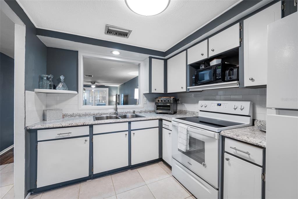 4210 Touchton Place, Unit 2 New Port Richey, FL 34652 - Photo 12 of 34 a kitchen with stainless steel appliances granite countertop white cabinets a sink and dishwasher
