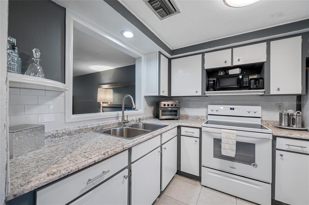 4210 Touchton Place, Unit 2 New Port Richey, FL 34652 - Photo 8 of 34 a kitchen with granite countertop a sink dishwasher stove and cabinets with wooden floor