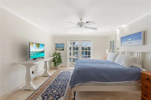 a spacious bedroom with a large bed a chandelier and windows