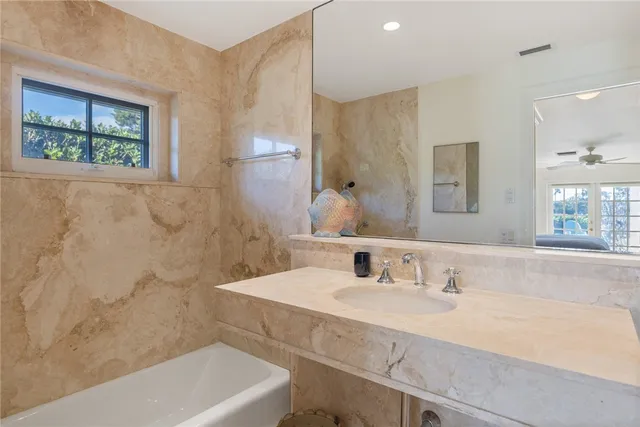 a bathroom with a granite countertop sink a large mirror a bathtub and next to a window