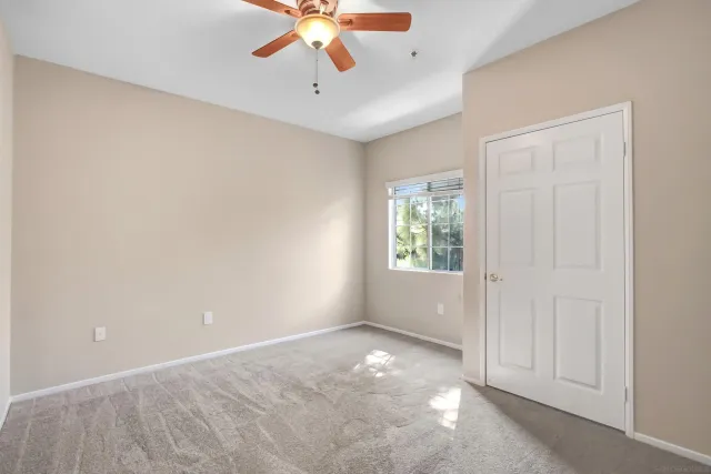 an empty room with windows and chandelier fan