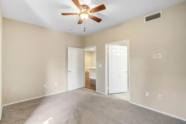 an empty room with chandelier fan and windows