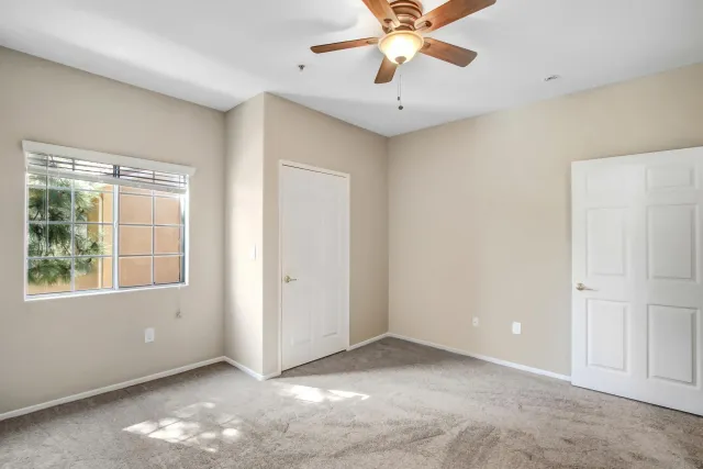 an empty room with chandelier fan and windows