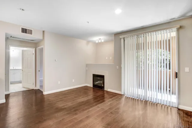 an empty room with wooden floor fireplace and windows