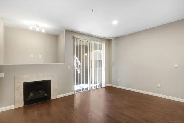 a view of an empty room with wooden floor and a fireplace