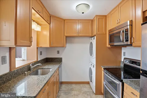 a kitchen with granite countertop a sink a stove cabinets and refrigerator