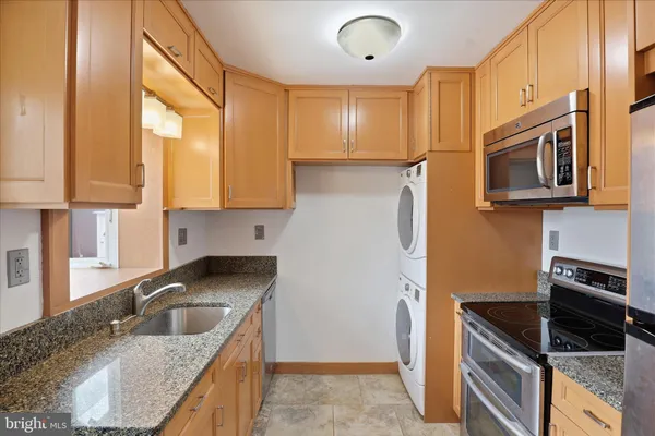 a kitchen with granite countertop a sink a stove cabinets and refrigerator