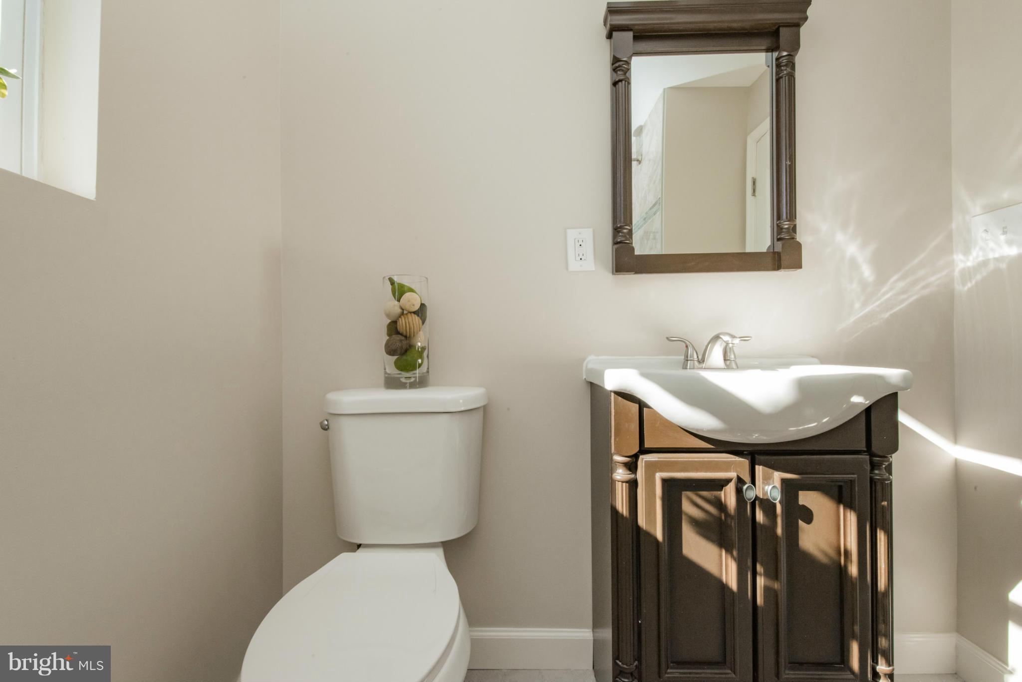 6922 Reisterstown Road Baltimore, MD 21215 - Photo 17 of 30 a bathroom with a toilet a sink and mirror