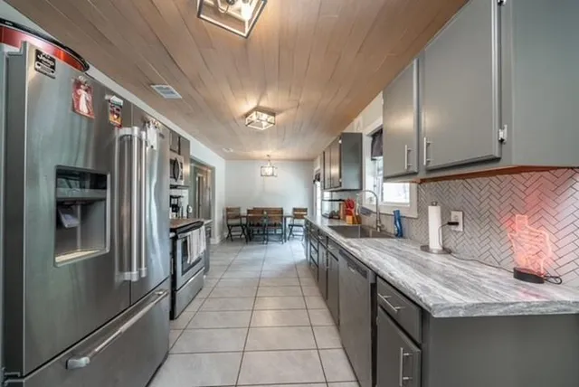 a kitchen with stainless steel appliances granite countertop a sink a stove and a refrigerator