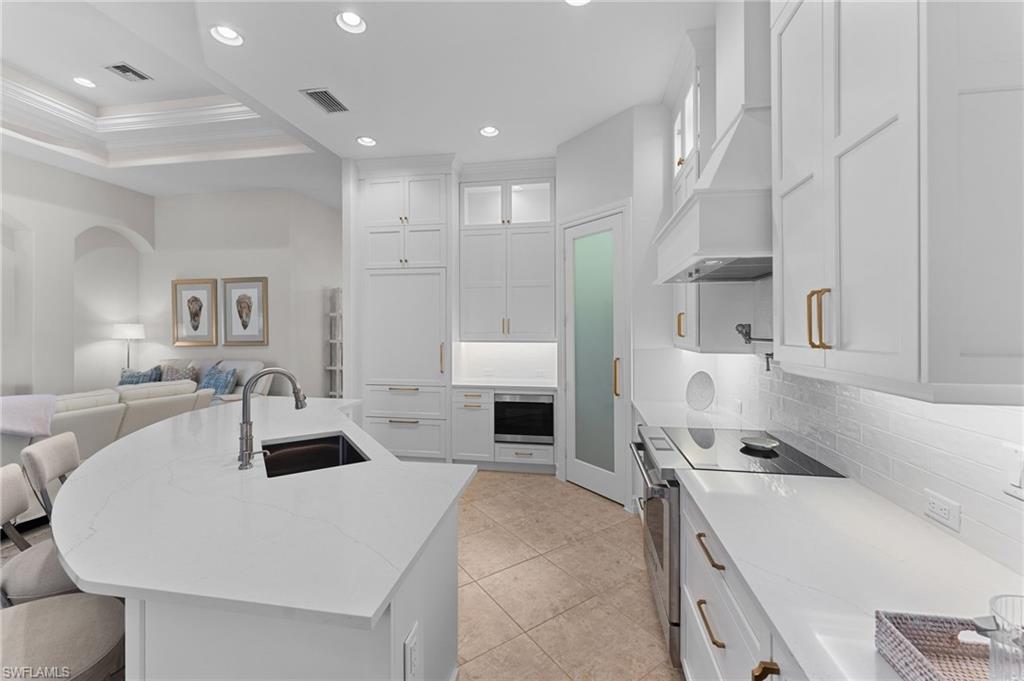 7831 Valencia Court Naples, FL 34113 - Photo 23 of 39 a kitchen with a sink a stove and white cabinets