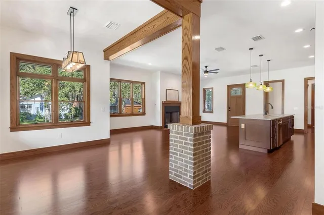 a view of an empty room with wooden floor and windows