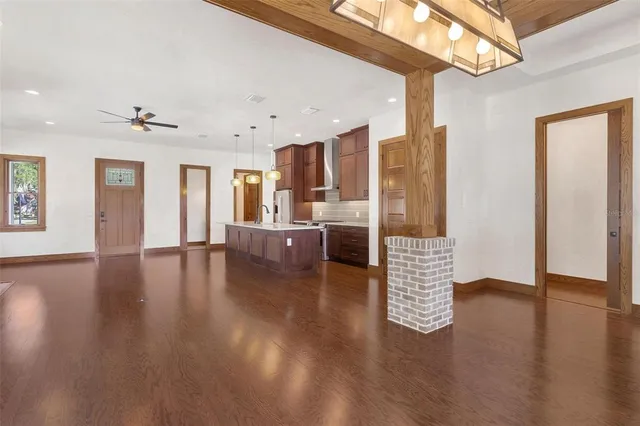 a view of an empty room with wooden floor and a kitchen