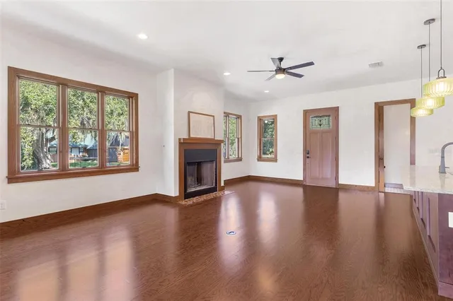 an empty room with windows fireplace and wooden floor